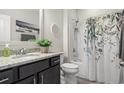 Well-lit bathroom featuring shower with patterned curtain, granite countertop, and decorative accents at 232 Red Maple Loop, Longs, SC 29568
