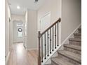 Inviting hallway with hardwood floors, stairs and natural light coming through front door at 232 Red Maple Loop, Longs, SC 29568
