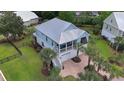 Two-story beach house with a metal roof, a brick driveway, a second story deck, and palm trees at 374 Graytwig Circle, Murrells Inlet, SC 29576