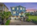 Two-story home at dusk featuring a meticulous brick driveway, two-car garage, and beautiful landscaping, including mature palm trees at 4832 Williams Island Dr., Little River, SC 29566