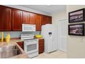 Well-lit kitchen with wooden cabinets, white appliances, and neutral countertops offers practical cooking space at 5840 Longwood Dr. # 303, Murrells Inlet, SC 29576