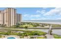 Aerial view showcasing the ocean, landscaping, and a tall high-rise building with multiple balconies at 101 Ocean Creek Dr. # Dd7, Myrtle Beach, SC 29572