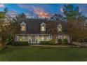 Evening view of a two story home with dormer windows and inviting curb appeal under a colorful sky at 2170 Deerfield Ave., Surfside Beach, SC 29575