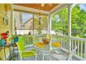Cozy screened-in porch with a glass table, wicker chairs, and a view of the surrounding greenery at 305 Goddard Ln., Murrells Inlet, SC 29576