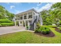 Two-story home with a staircase leading to the balconies and lush landscaping at 476 Lakeshore Dr., Pawleys Island, SC 29585