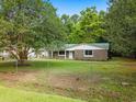 This single story home features stone accents, a green metal roof, and a charming fenced yard with mature trees at 96 Middleton Rd., Andrews, SC 29510