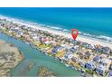 An aerial view showcasing coastal homes nestled between the ocean and marsh at 969 S Waccamaw Dr., Garden City Beach, SC 29576
