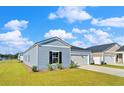 Single-story home with light blue siding, a well-manicured lawn, and an attached one car garage at 1004 Sentinel Ct., Little River, SC 29566