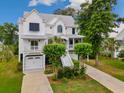 Stunning home featuring a metal roof, double garages, lush landscaping, and an inviting entrance at 166 Cayman Loop, Pawleys Island, SC 29585