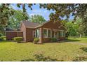 A quaint brick home with a lush green lawn surrounded by mature trees and landscaping at 1895 Bucksville Dr., Conway, SC 29527