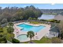 Inviting community pool surrounded by lounge chairs, palm trees, and a scenic lake backdrop at 151 Chenoa Dr. # 35-F, Murrells Inlet, SC 29576