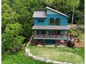 Two-story blue home with metal roof surrounded by lush greenery and a stone-lined landscape at 329 Kaufman St., Georgetown, SC 29440