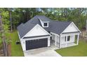 Lovely home with a dark garage door, white siding, and black roof nestled in a wooded setting at 4120 Whatuthink Rd., Myrtle Beach, SC 29588