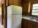 Classic kitchen view highlighting a white refrigerator, wood cabinets, and a double basin sink at 444 Davis Rd., Hemingway, SC 29554