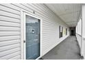 Hallway view of unit entrance with a storm door and light-colored vinyl siding at 4811 Innisbrook Ct. # 306, Myrtle Beach, SC 29579