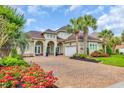 Beautiful landscaped home with brick driveway, lawn and flowerbeds, and palm trees at 603 Sea Island Way, North Myrtle Beach, SC 29582