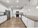 Modern kitchen features white cabinets, granite countertops, stainless steel appliances and wood flooring at 1124 Valetto Loop, Myrtle Beach, SC 29579