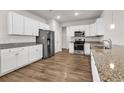 Modern kitchen features white cabinets, granite countertops, stainless steel appliances and wood flooring at 1124 Valetto Loop, Myrtle Beach, SC 29579