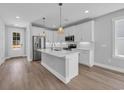 Modern kitchen with white cabinets, stainless steel appliances, island with seating and pendant lighting at 1961 Indigo Cove Ln, Calabash, NC 28467