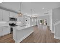 Bright, open kitchen featuring white cabinetry, stainless appliances, and a large island with pendant lighting at 1961 Indigo Cove Ln, Calabash, NC 28467