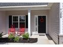 Inviting front porch featuring two red rocking chairs, a wreath on the black front door, and manicured landscaping at 206 N Levee Dr., Georgetown, SC 29440