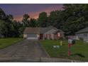 Inviting single-story home with landscaped front yard and driveway, set against a backdrop of mature trees and an evening sky at 271 Sienna Dr., Little River, SC 29566