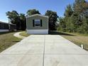 Long concrete driveway leads up to a light green single-story home with neatly kept lawn at 400 Cessna St, Myrtle Beach, SC 29577