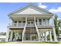 Inviting stilt home featuring a spacious porch, a double staircase, and bright natural lighting at 400 Elizabeth Dr., Murrells Inlet, SC 29576