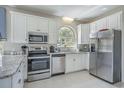 Well-lit kitchen with stainless steel appliances, ample white cabinetry, granite counters, and tiled flooring at 500 23Rd Ave. S, North Myrtle Beach, SC 29582