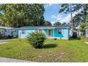 Charming home featuring a well-manicured lawn, teal siding and purple shutters, creating a welcoming curb appeal at 1107 Blue Ridge Trail, North Myrtle Beach, SC 29582