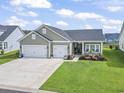 Charming home featuring an attached two car garage, green lawn and landscaping at 122 New Paradise Way, Myrtle Beach, SC 29588