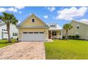 Inviting yellow home with brick driveway, a pristine garage, and lush green lawn under a bright blue sky at 323 Waties Dr., Murrells Inlet, SC 29576