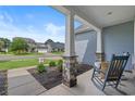 Cozy rocking chair on a covered front porch with stone supports and a view of the neighborhood at 3620 Diamond Stars Way, Little River, SC 29566