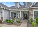 Inviting front porch with decorative columns, stone accents, and a cozy seating area with landscaped garden at 3620 Diamond Stars Way, Little River, SC 29566