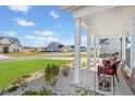 Inviting covered porch with white columns, a seasonal flag, chairs, and manicured landscaping at 4000 Da Vinci Dr., Myrtle Beach, SC 29579