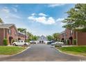 View of well-maintained townhome exteriors with black awnings, parking area, and green landscaping at 404 1St Ave. N # H, North Myrtle Beach, SC 29582