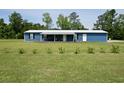 Blue single-story home featuring a covered front porch and well-maintained lawn with garden at 445 W Willow Pond Rd., Johnsonville, SC 29555