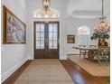 Elegant foyer featuring a double-door entrance, hardwood floors, a jute rug, and decorative chandelier at 7202 Seville Dr., Myrtle Beach, SC 29572