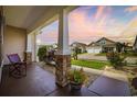 Inviting covered porch with stone accents, offering a relaxing outdoor seating area with colorful plants at 605 Ginger Lily Way, Little River, SC 29566
