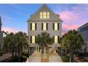 Lovely stilted home featuring bright windows and dark shutters, surrounded by lush palm trees, creating a tropical paradise at 703 S Waccamaw Dr., Garden City Beach, SC 29576