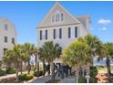 Beautiful coastal home on stilts with palm trees and beach access, perfect for relaxed seaside living at 703 S Waccamaw Dr., Garden City Beach, SC 29576
