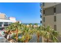 Exterior view of resort, ocean, and pool area framed by lush palm trees on a sunny day at 7200 N Ocean Blvd. # 360, Myrtle Beach, SC 29572