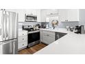 Renovated kitchen with stainless steel appliances, white cabinets, light countertops, and modern fixtures at 917 S Ocean Blvd. # 103, Surfside Beach, SC 29575