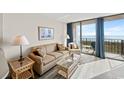 Bright living room with cozy seating, ocean view, and balcony access through sliding glass doors at 1501 Ocean Blvd. S # 103, North Myrtle Beach, SC 29582