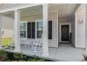 Inviting covered front porch with white rocking chairs, black shutters, and a welcoming wreath on the front door at 179 Empyrean Circle, Myrtle Beach, SC 29588
