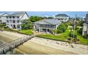 Beautiful aerial view of a coastal home with a pier leading to the beach and waterfront at 1924 Pompano Dr., Garden City Beach, SC 29576