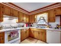 Traditional kitchen featuring wooden cabinets, white appliances, and a window above a stainless-steel sink at 4810 Circle Dr., Loris, SC 29569