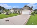 A beautifully landscaped, single-story home featuring an expansive driveway and a welcoming two-car garage at 505 Joy Way Ct., Longs, SC 29568