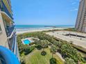 Expansive ocean view from a condo balcony, showcasing the beach, pier, pool, and lush green landscaping at 8560 Queensway Blvd. # 508, Myrtle Beach, SC 29572