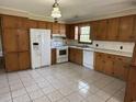 Traditional kitchen featuring wood cabinets, white appliances, and a tile floor at 1002 S Beech Ave., Andrews, SC 29510